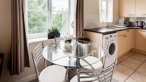 Una cocina moderna con una mesa de vidrio, lavadora y un lavabo.