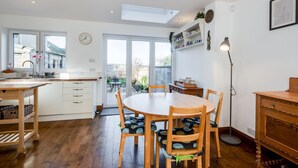 A modern kitchen with a dining area, wooden flooring, and a skylight. - Charming 3 BR House - Garden Parking Near CS Lewis Park (Oxford)
