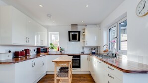 A modern kitchen with white cabinets, a wooden countertop, and a central island. - Charming 3 BR House - Garden Parking Near CS Lewis Park (Oxford)