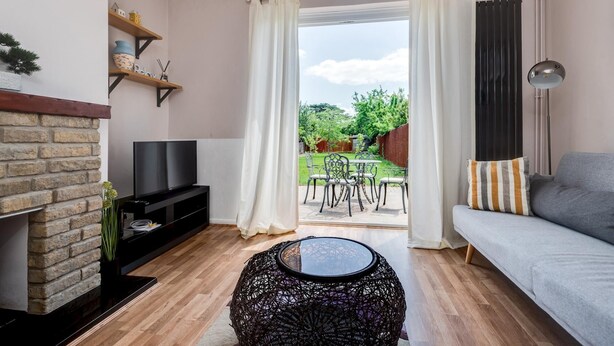 Una sala de estar con televisor, chimenea, sofá y un comedor con sillas y mesa.