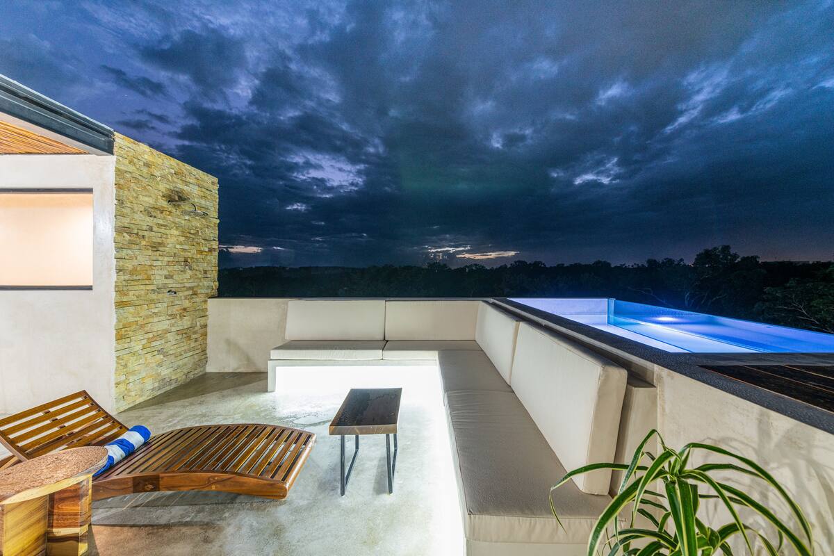 Ein moderner Balkon mit Sitzgelegenheit, einem kleinen Tisch und Blick zum Himmel.