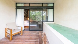 A balcony with a wooden chair, a bed with a view, and a green cushioned bench. - Irie Tulum  (Tulum)