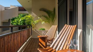 A balcony with wooden furniture, including a chair and a small table, and two wine glasses on the table.