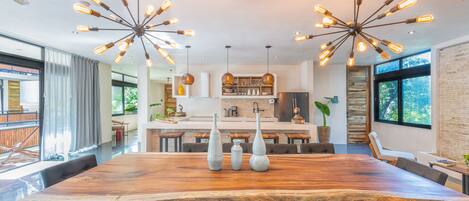 A spacious dining area with a large wooden table, multiple chairs, and three tall vases.