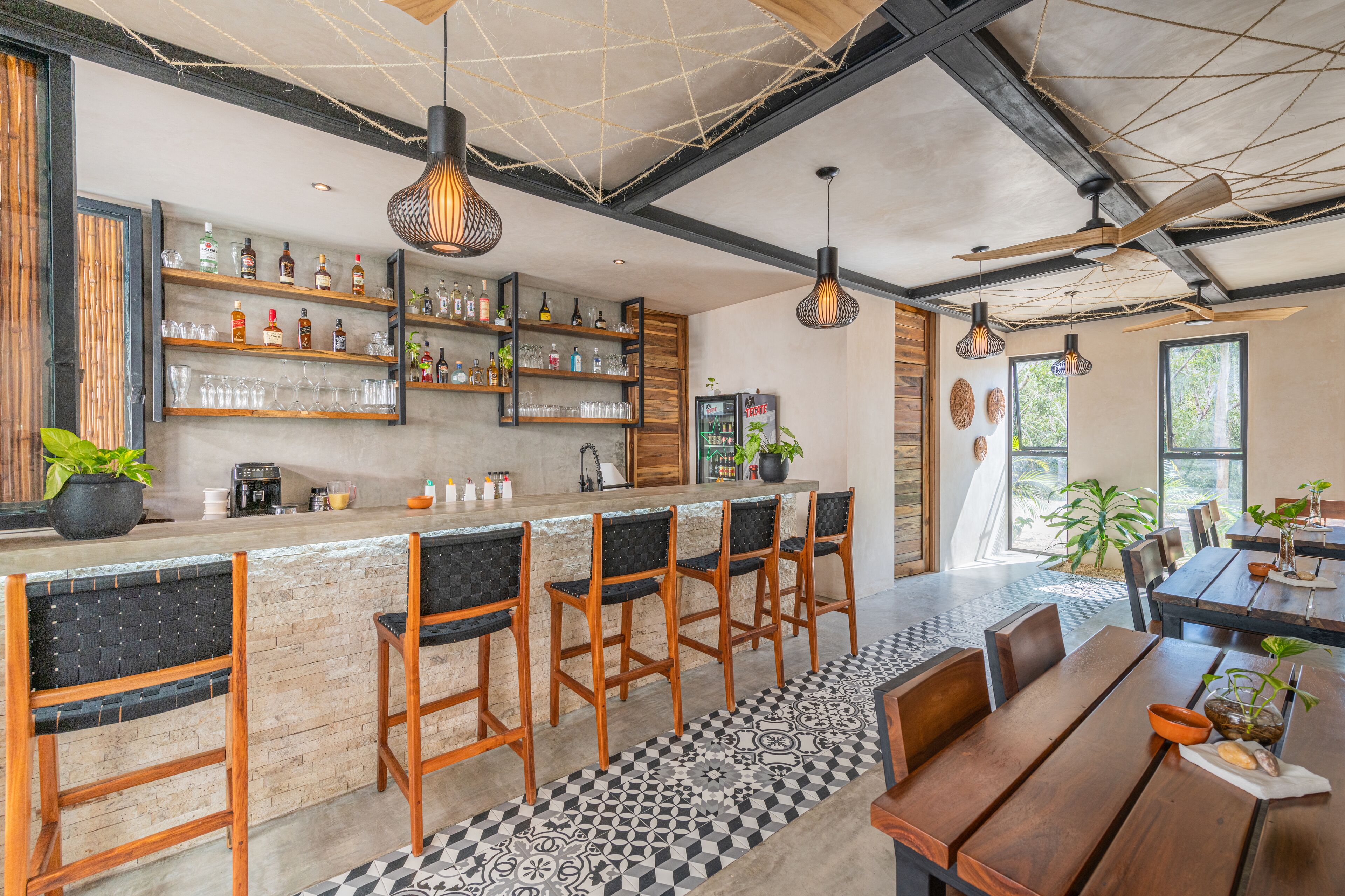 A bar area with wooden chairs, a counter with bottles, and a ceiling fan.