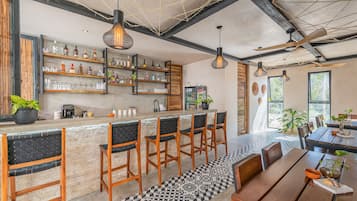A bar area with wooden chairs, a counter with bottles, and a ceiling fan.