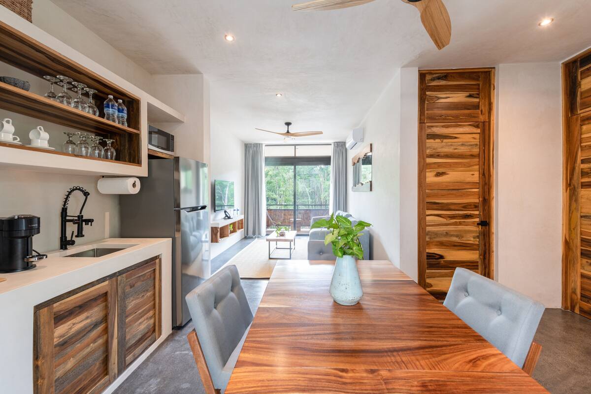 Eine moderne Küche mit Holzschränken, einer integrierten Kochinsel und einem Essbereich mit Holztisch und Stühlen.