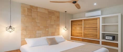 A bedroom with a large bed, wooden headboard, built-in wardrobe, and pendant lights.