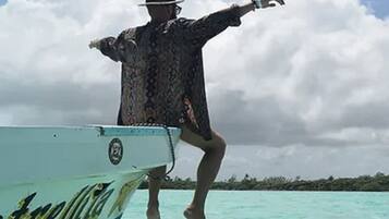A person leaping off a boat with a tropical landscape in the background.