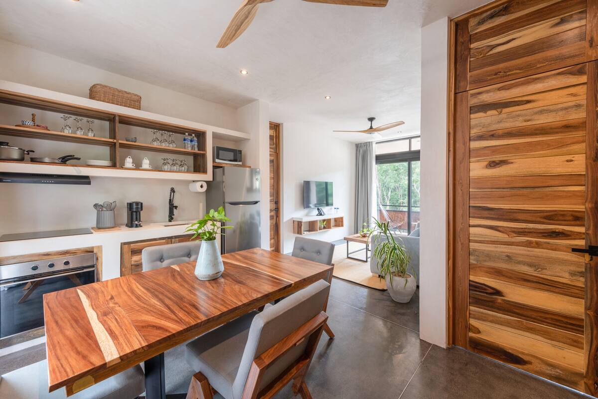 Eine moderne Küche mit Holzböden, einem Esstisch und einer großen Holztür.