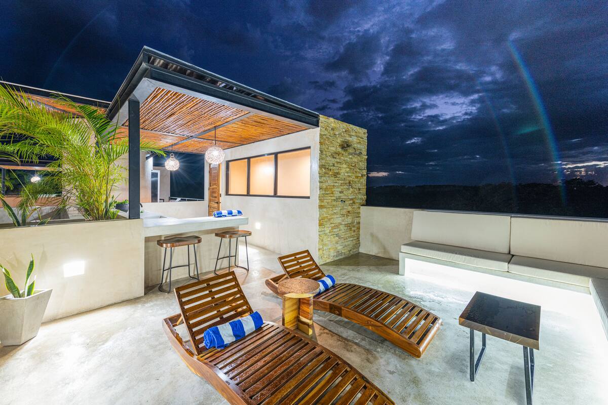 Eine Außenpatio mit Holzliegen, einer Bar und Blick auf den Nachthimmel.