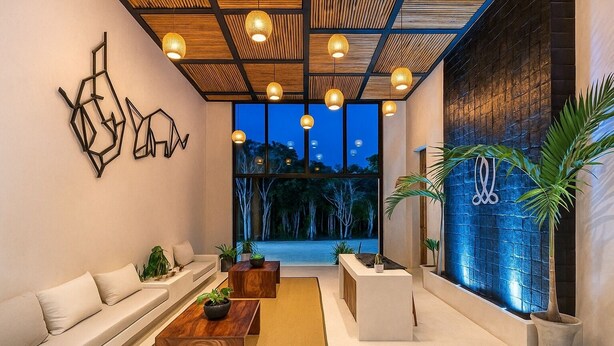 A modern interior with a wooden ceiling, a sofa, a coffee table, and a view of trees outside. - Irie Tulum  (Tulum)