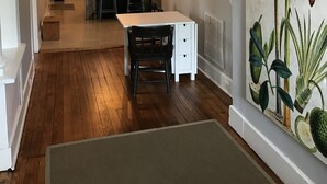 Une cuisine spacieuse avec un coin repas, un plancher en bois et une grande estampe représentant des motifs végétaux accrochée au mur.