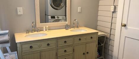 A bathroom with two sinks, a large mirror, and a washing machine in the background.