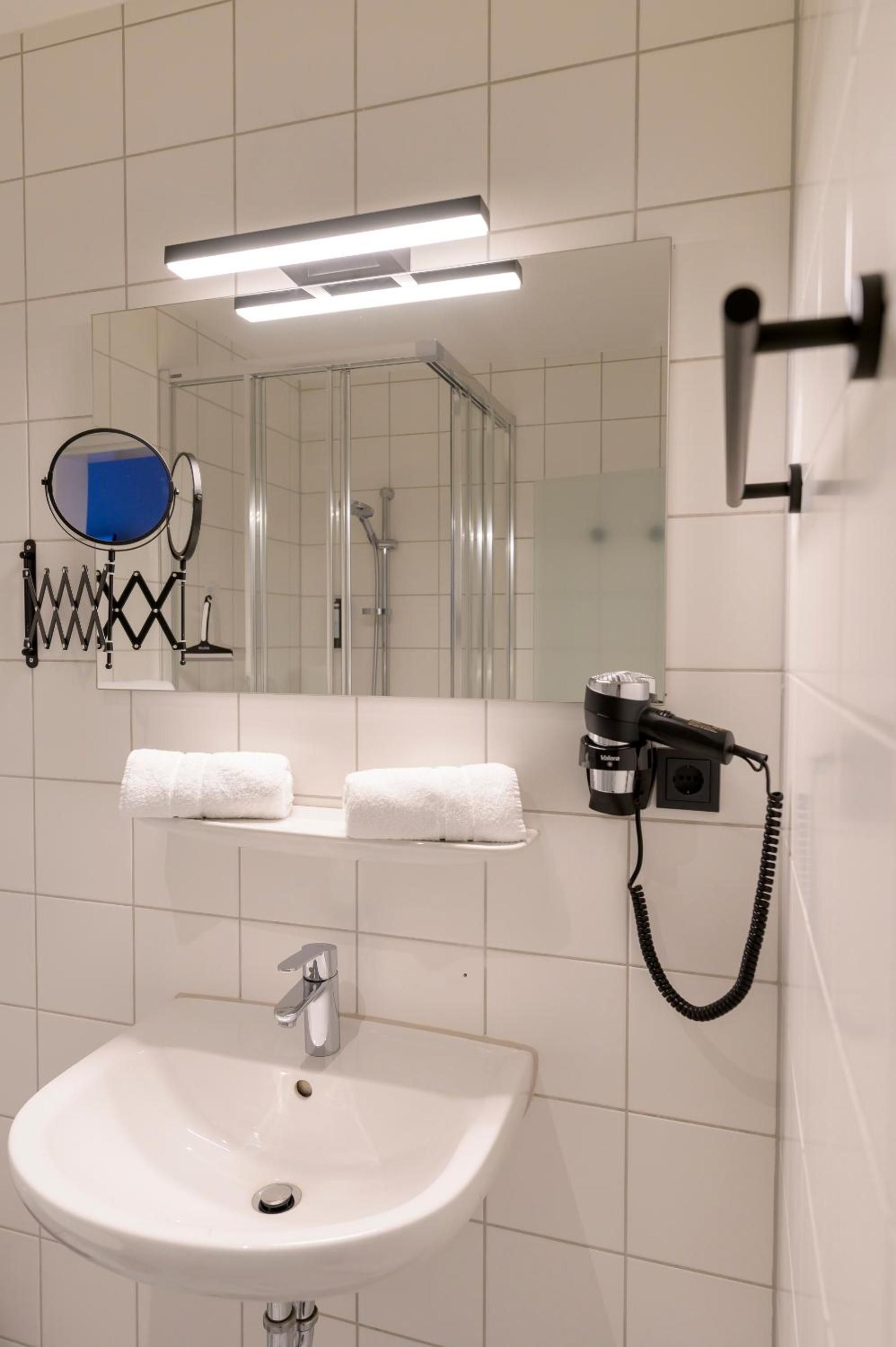A bathroom with a sink, mirror, towel rack, and hairdryer.
