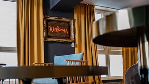 Una habitación con una silla de madera, un cojín azul, un cartel que dice 'Welcome' y una alfombra estampada.