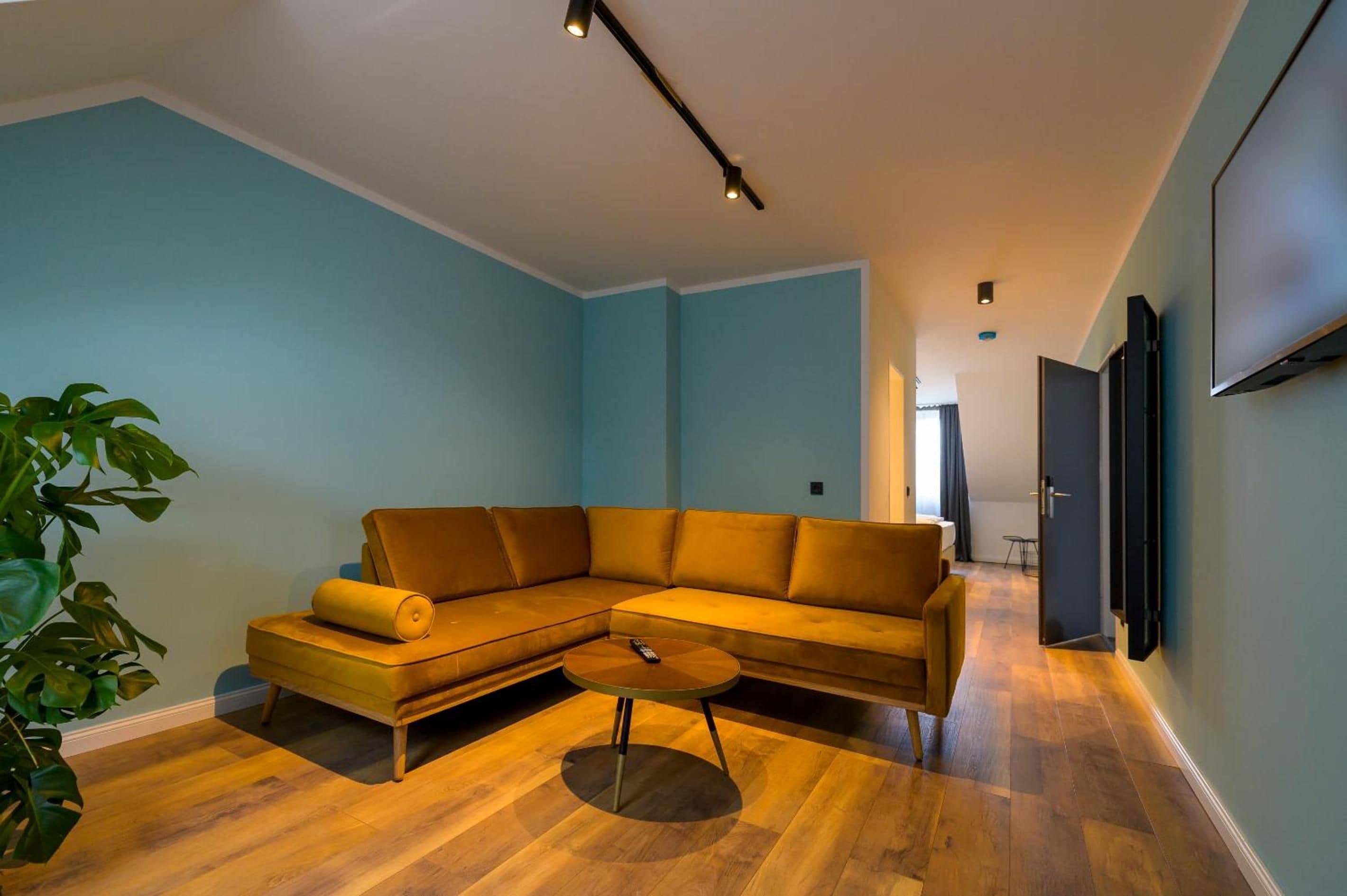 A living room with a sectional sofa, a coffee table, and a plant.