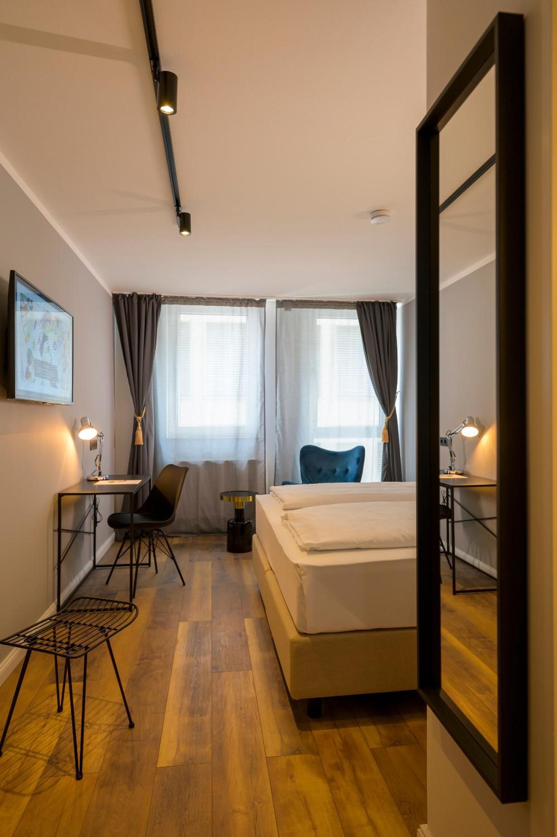 Una habitación de hotel con cama, escritorio, silla, mesita y espejo.