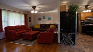 Un salon avec un ensemble de canapés rouges, un plancher en bois et un ventilateur de plafond.