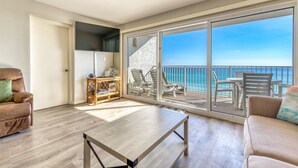 Un ampio balcone con vista sul mare, arredato con sedie e un tavolo.