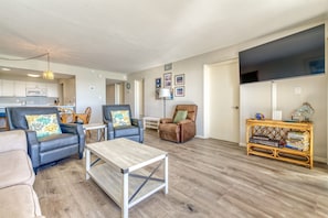 Ein modernes Wohnzimmer mit Sofa, Sesseln, Couchtisch und Fernseher.