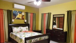 Un dormitorio con cama, cómoda, espejo y aire acondicionado.
