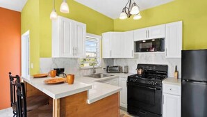 Cocina moderna con armarios blancos, una estufa negra y un refrigerador negro.