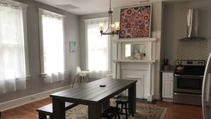 Cozinha moderna com área de refeições, destacando uma mesa de madeira, cadeiras, um lustre e uma lareira.