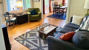 Un salon comprenant un canapé, un fauteuil, une table basse et un coin repas avec une table et des chaises.