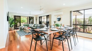 Amplia sala de estar con una mesa de comedor dispuesta para seis personas, rodeada de sillas negras.