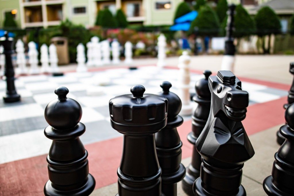 A chessboard with black and white pieces in a public outdoor area.