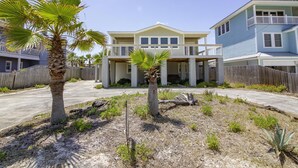 A two-story house with a covered front porch, a fenced yard, and a palm tree. - Charming Cottage ~ Steps to the Beach ~ Pet Friendly (Saint Augustine)