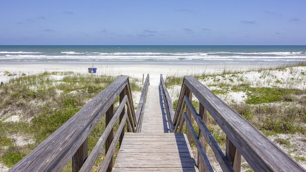 A wooden boardwalk leading to a beach with white sand and ocean waves. - Charming Cottage ~ Steps to the Beach ~ Pet Friendly (Saint Augustine)