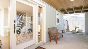 A wooden bench outside a house with a white door and a welcome mat. - Charming Cottage ~ Steps to the Beach ~ Pet Friendly (Saint Augustine)
