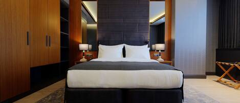 Une chambre d’hôtel moderne avec un grand lit, une armoire en bois et une tête de lit sombre.