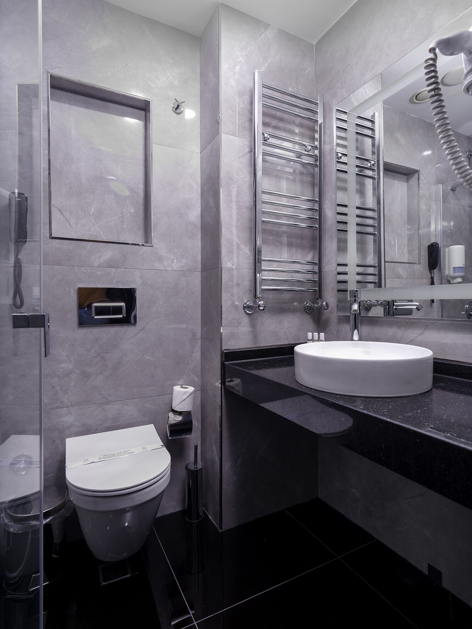 Un baño moderno con inodoro, bidé y un espejo grande sobre el lavamanos.