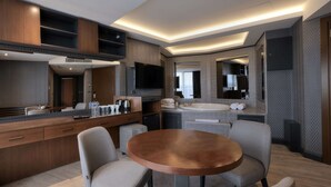 Une cuisine moderne dotée d’un îlot central, d’appareils électroménagers intégrés et d’un téléviseur à écran plat.