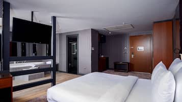 A modern hotel room with a large bed, a TV, a desk, and a bathroom with a shower and toilet.