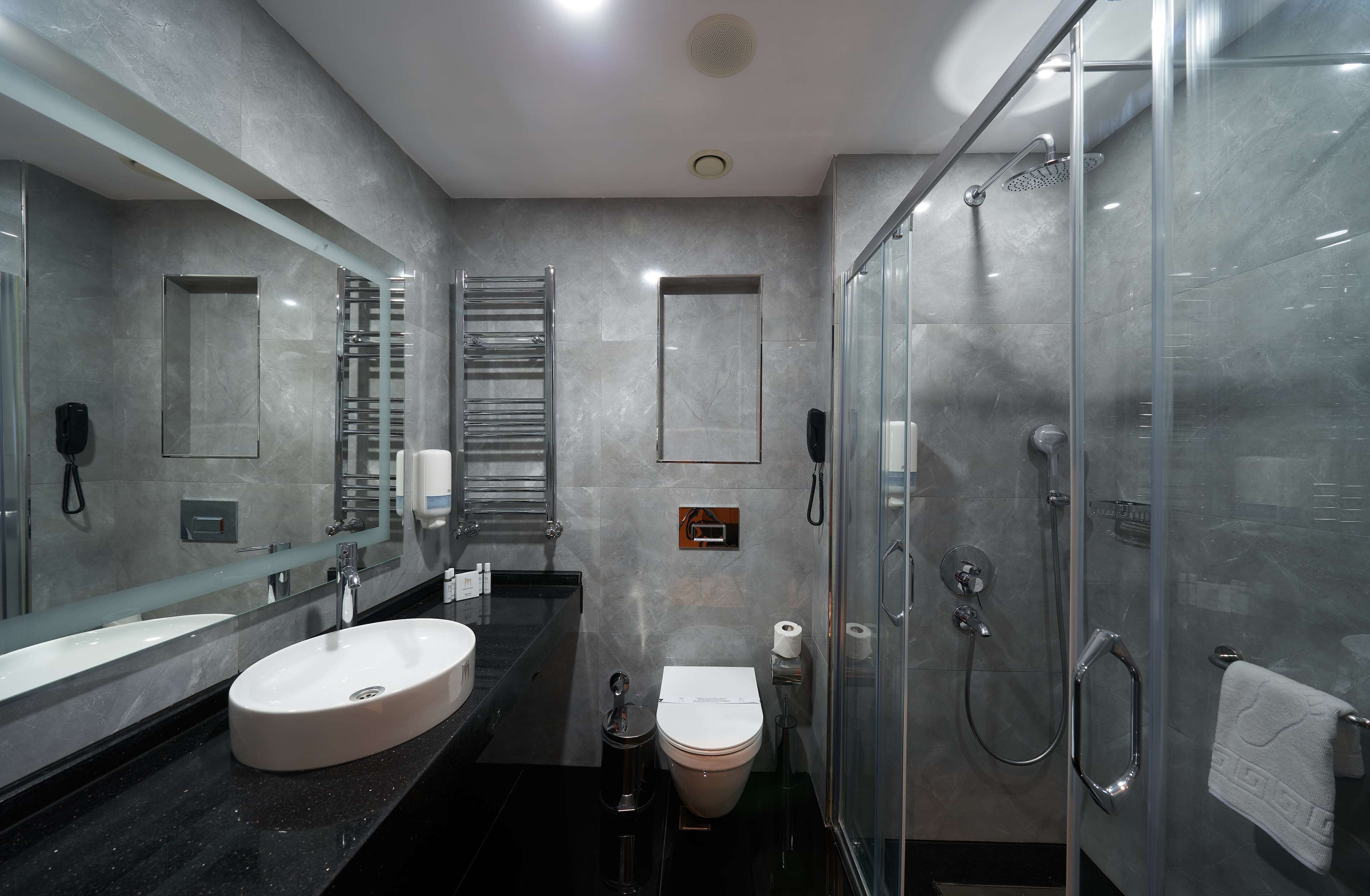 Een moderne badkamer met een grote spiegel, twee wastafels, een toilet en een douchecabine met glazen wanden.