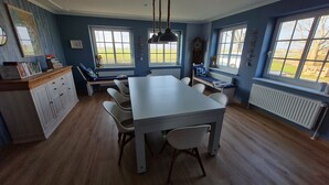 Un espace repas comprenant une table et des chaises, un banc, un radiateur et une fenêtre donnant sur l’extérieur.