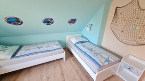 Een kamer met twee eenpersoonsbedden, een klein wit nachtkastje, een wandlamp en een decoratie van gaas.