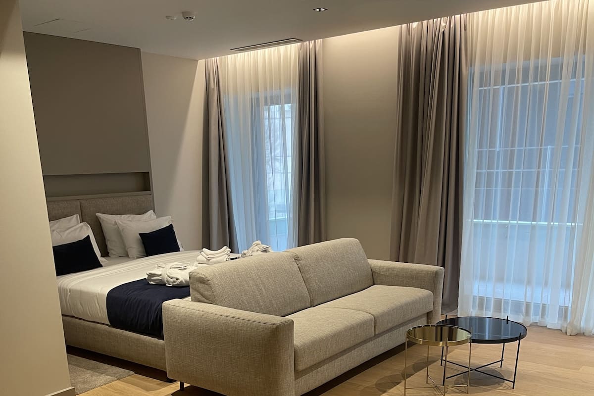 Ein modernes Wohnzimmer mit einer Couch, einem runden Tisch und einem Bett mit Kopfteil.