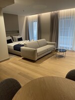 Uma sala de estar moderna com um sofá, uma mesa redonda e uma cama com cabeceira.
