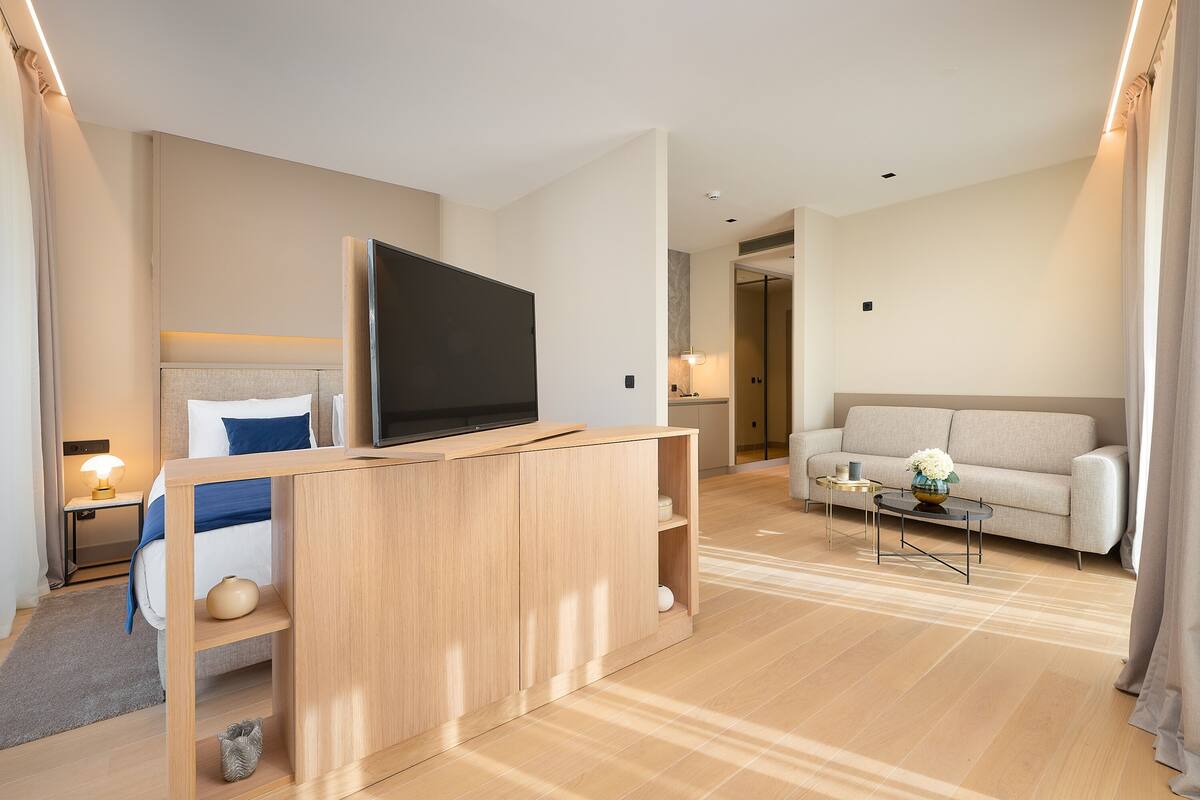 Ein modernes Hotelzimmer mit einem Bett, einem Fernseher, einer Couch und einem Couchtisch.