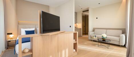 A modern hotel room with a bed, a TV, a sofa, and a coffee table.