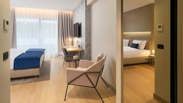 A modern hotel room with a bed, a desk, a chair, and a TV.