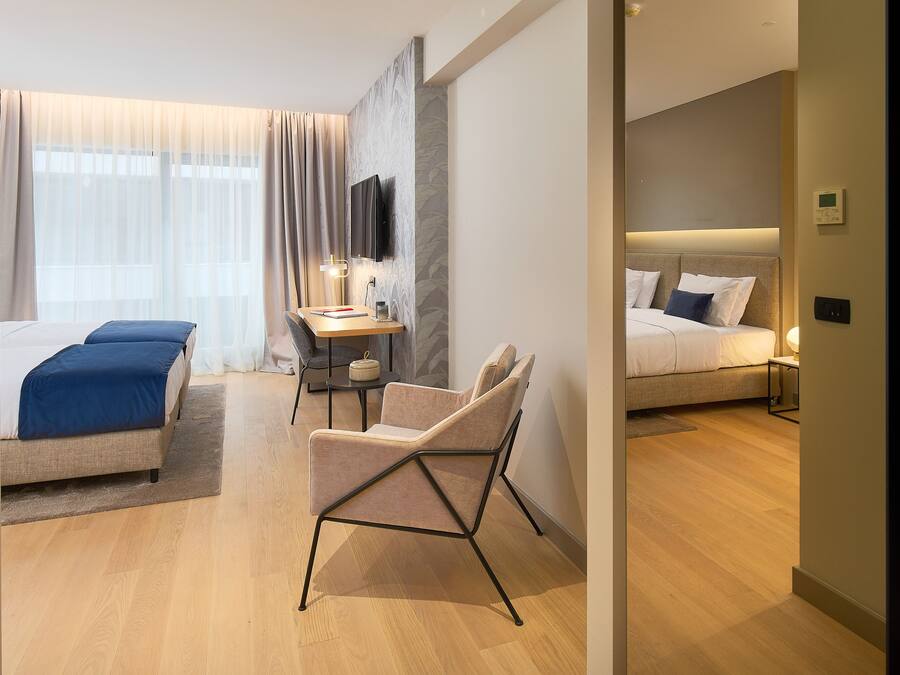 A modern hotel room with a bed, a desk, a chair, and a TV.
