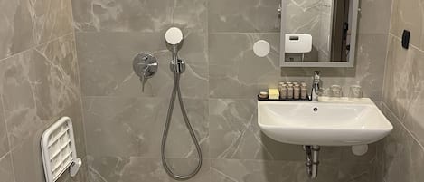 Un baño moderno con ducha a nivel, lavabo y espejo.