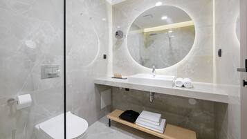 Een moderne badkamer met een marmeren wastafel, een ronde spiegel en een inloopdouche.