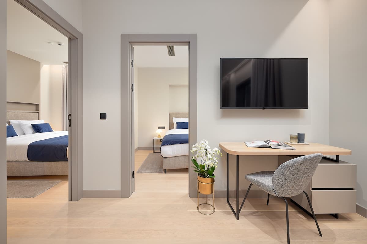 Ein modernes Hotelzimmer mit einem Bett, einem Schreibtisch, einem Stuhl, einem Fernseher und einer Topfpflanze.